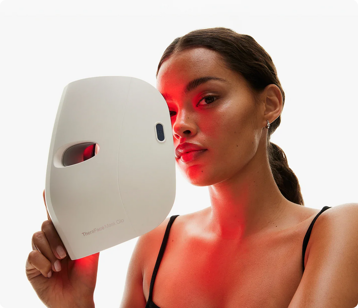 Woman holding a white LED face mask with red light on a white background