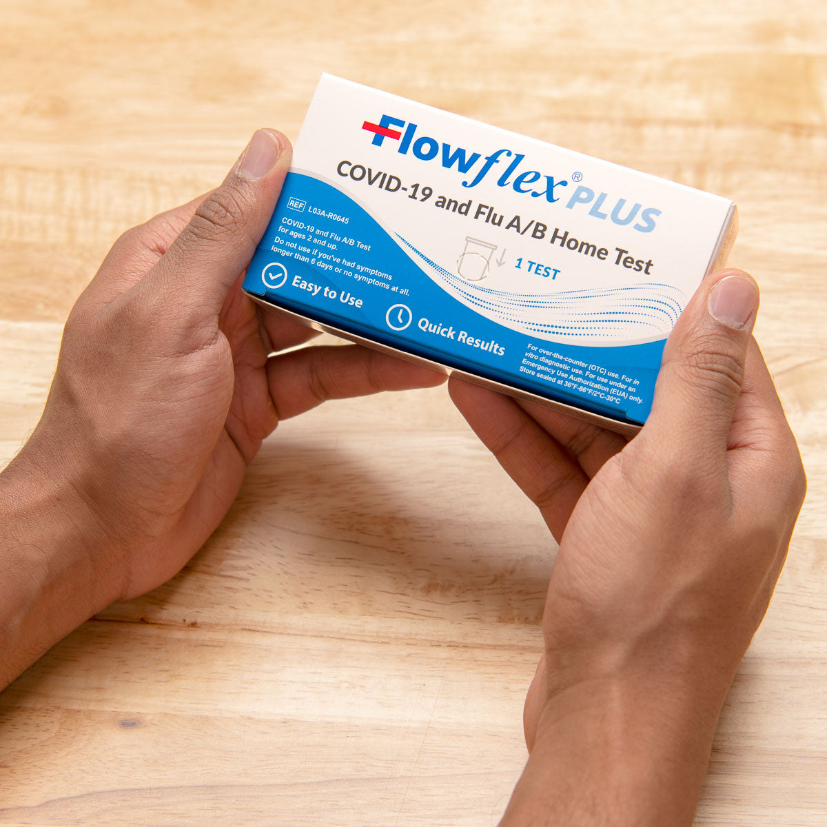 Hands holding Flowflex Plus COVID-19 and Flu A/B home test kit box
