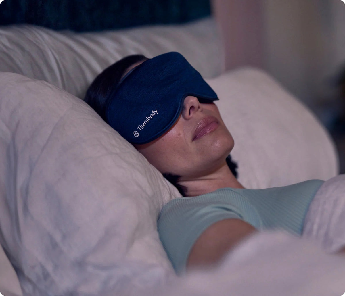 Women wearing Therabody SleepMask while resting in bed