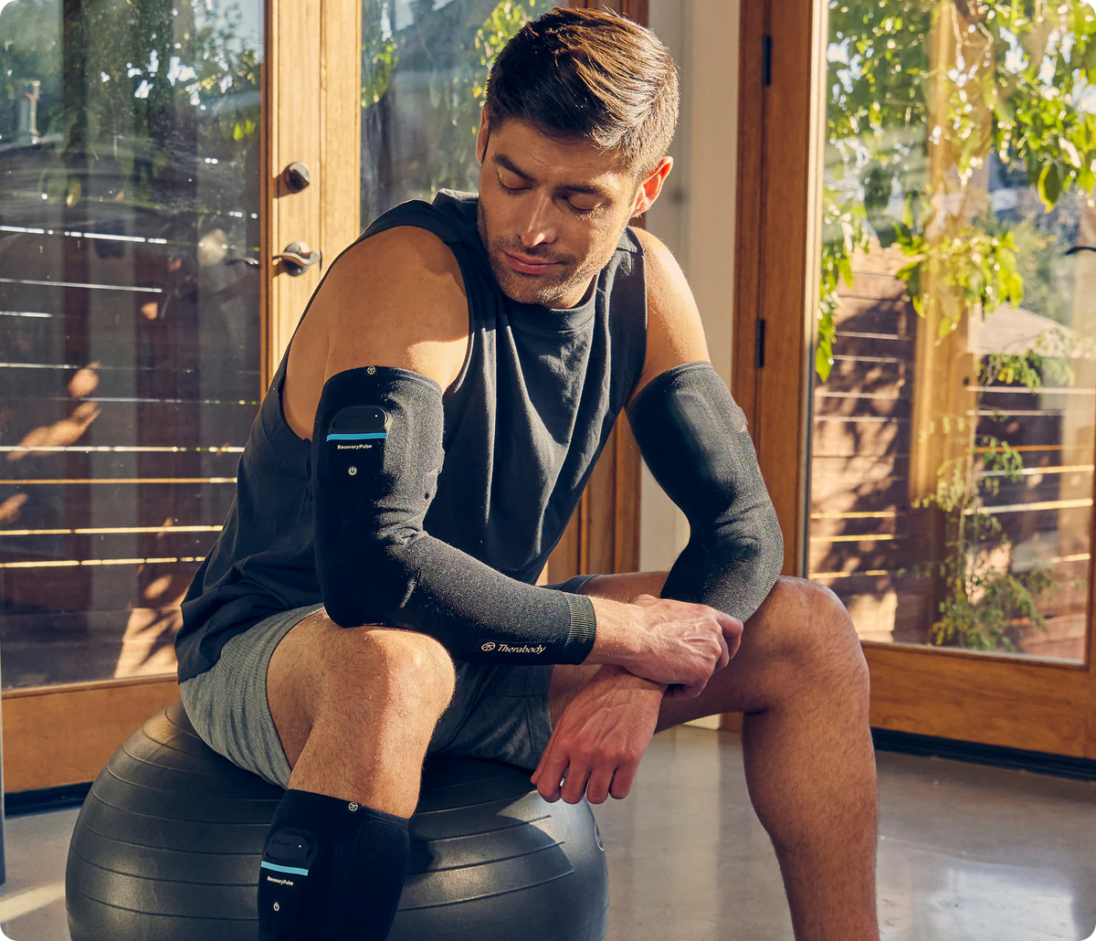 Athlete wearing Therabody RecoveryPulse Arm sleeve during post-workout recovery