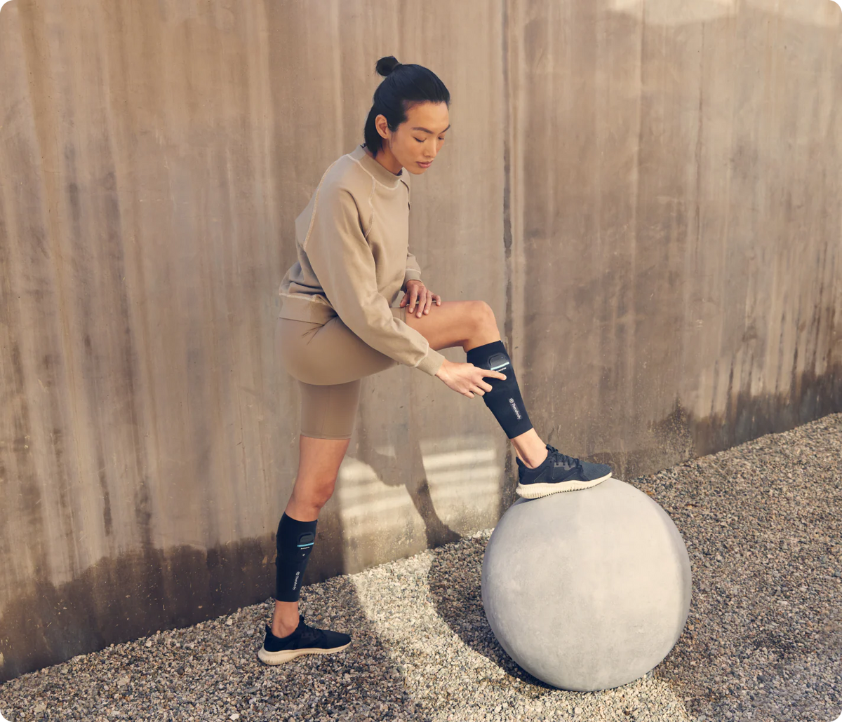 Women wearing Therabody RecoveryPulse Calf device during post-workout recovery