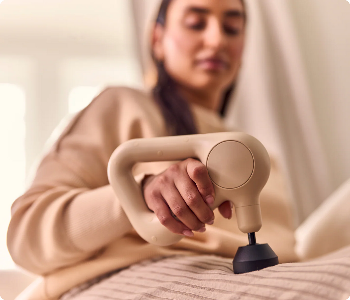 Women using a handheld massager on a bed
