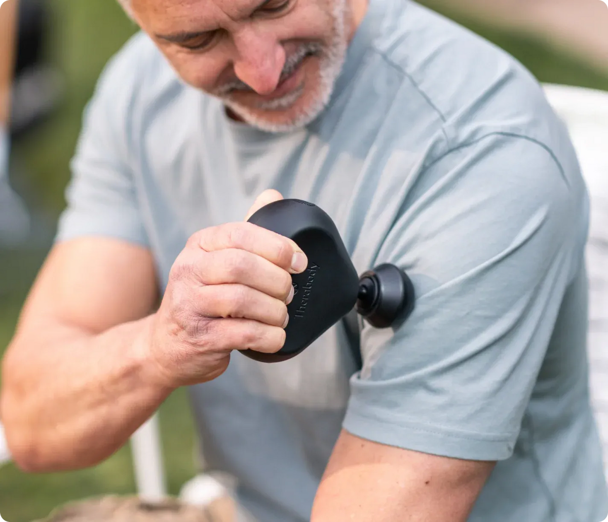 Person using Theragun Mini 3rd Gen portable massage gun on arm muscles