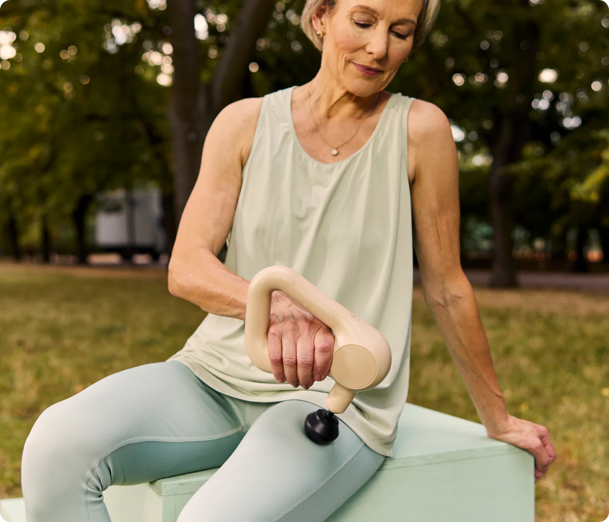 Woman using Theragun Relief (Sand) Percussion Massage Gun outdoors
