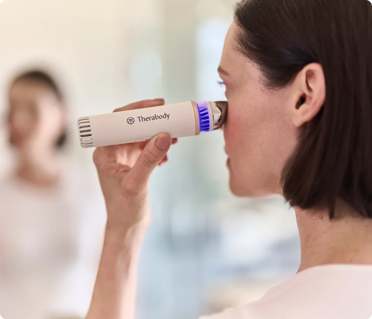 Woman applying a handheld LED skincare device to support facial skin health and rejuvenation
