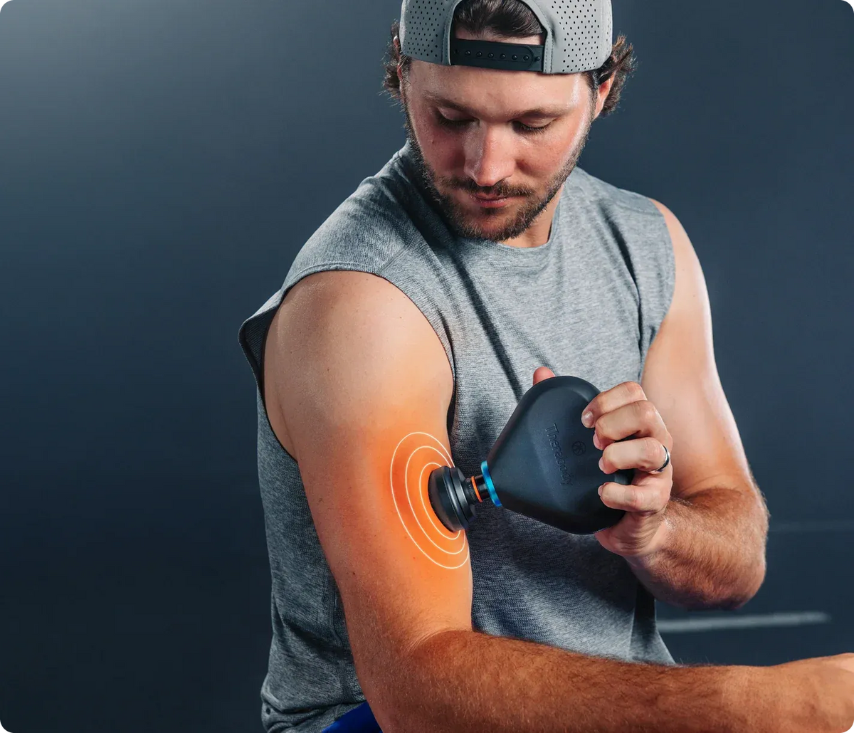 Man using a black massage device on his arm