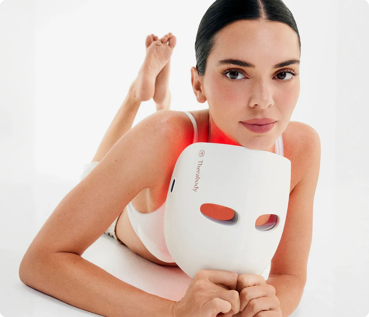 Model holding an LED light therapy face mask during a skincare treatment session