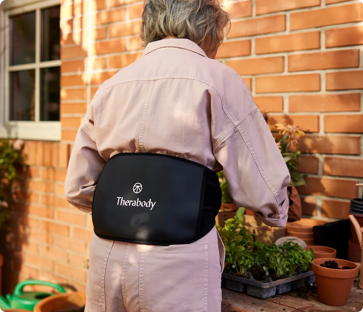 Old Person wearing ThermBack LED 4-in-1 Back Wrap while gardening for convenient back therapy
