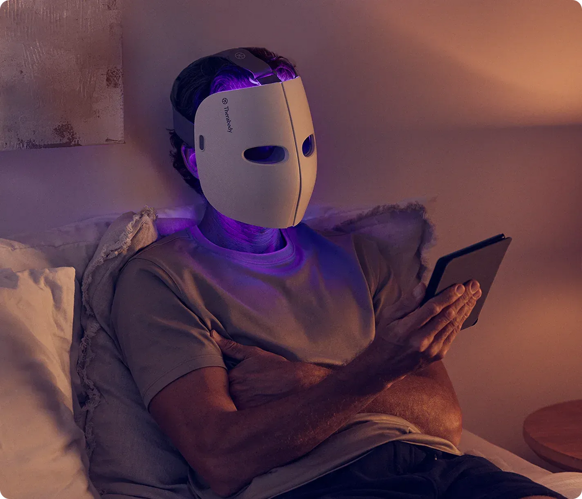 Person wearing Therabody TheraFace Mask while relaxing in the evening
