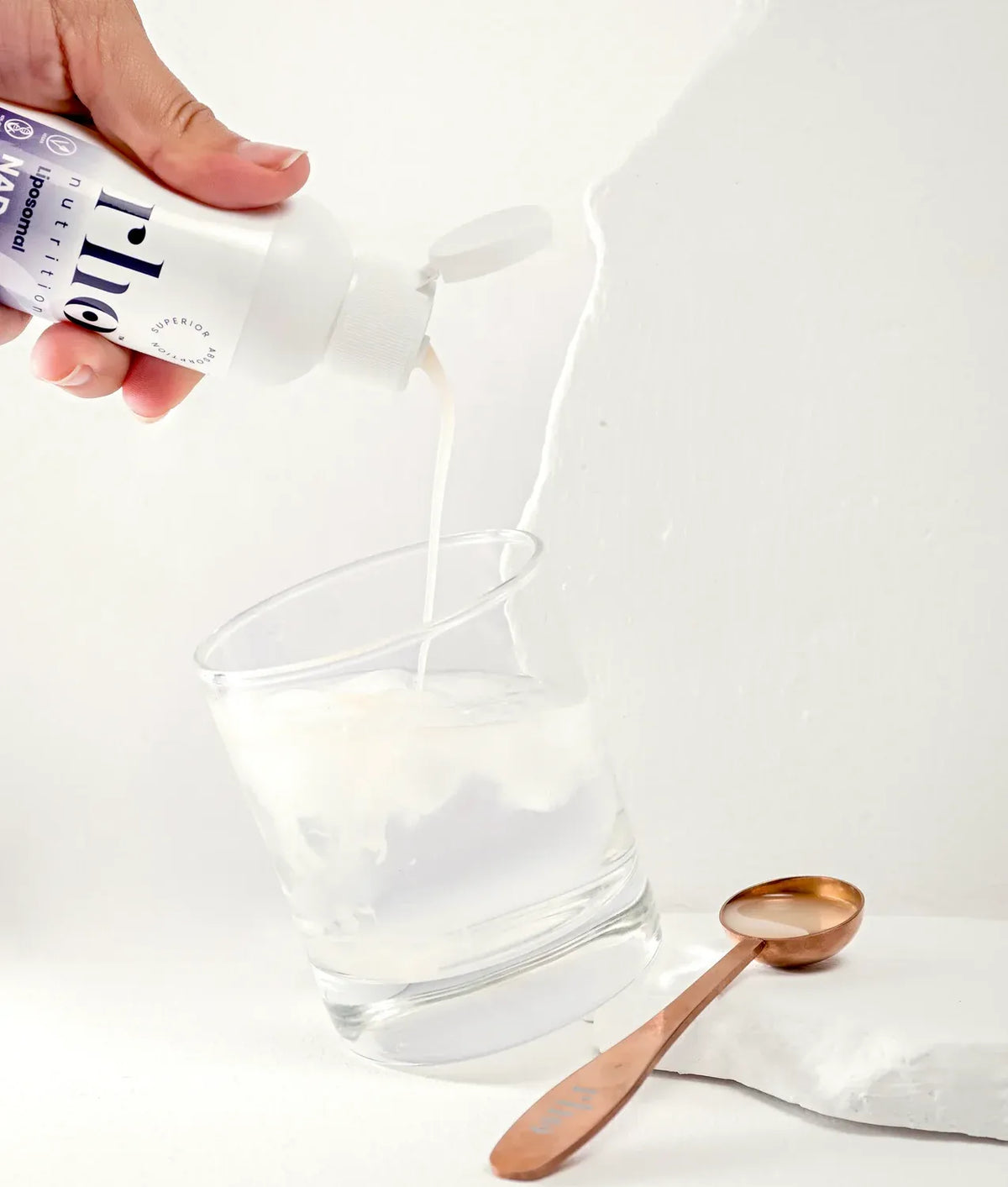 Pouring Rho Nutrition Liposomal NAD+ into water with measuring spoon