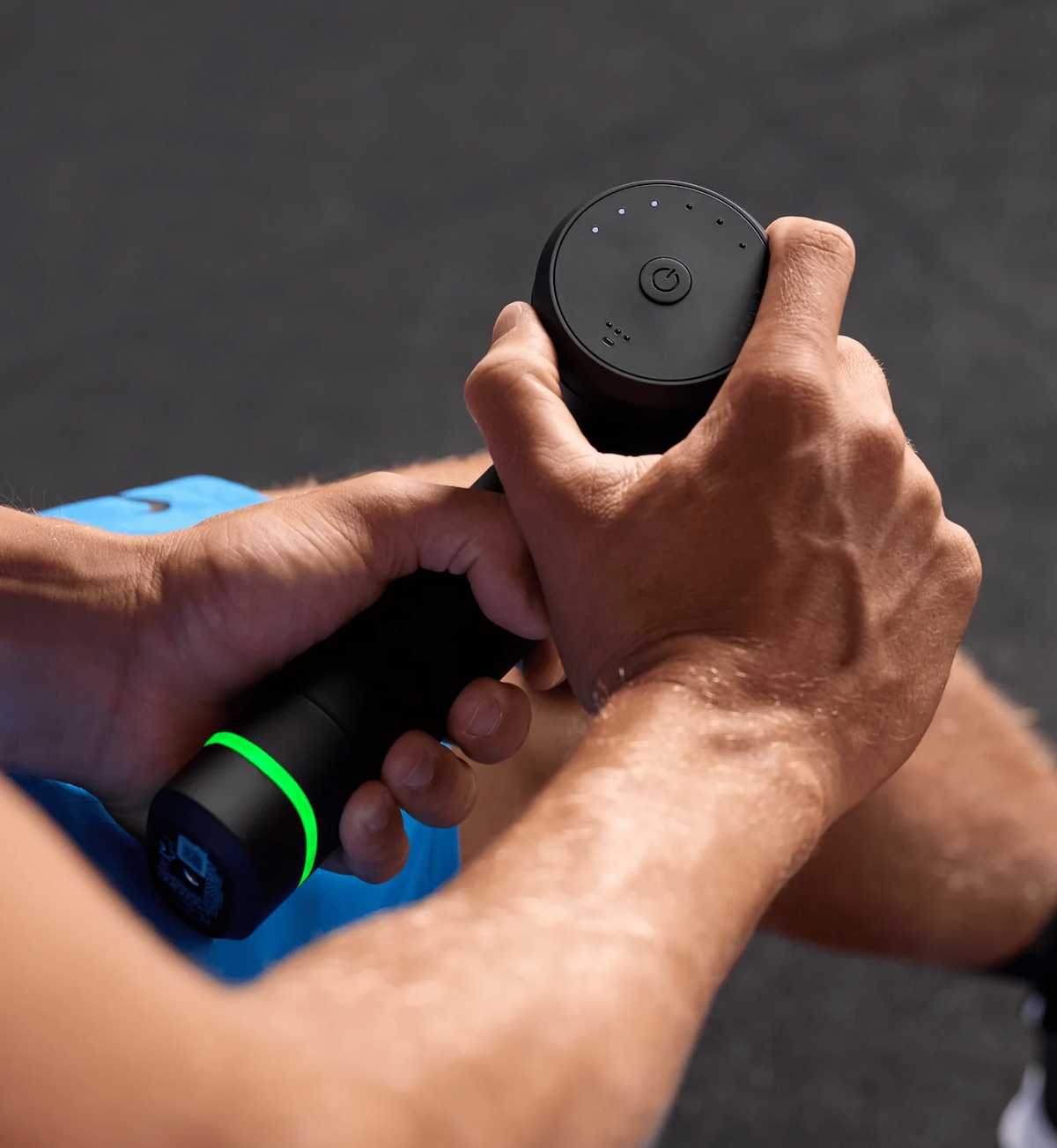 Person holding a black handheld device with a green light on a blurred background