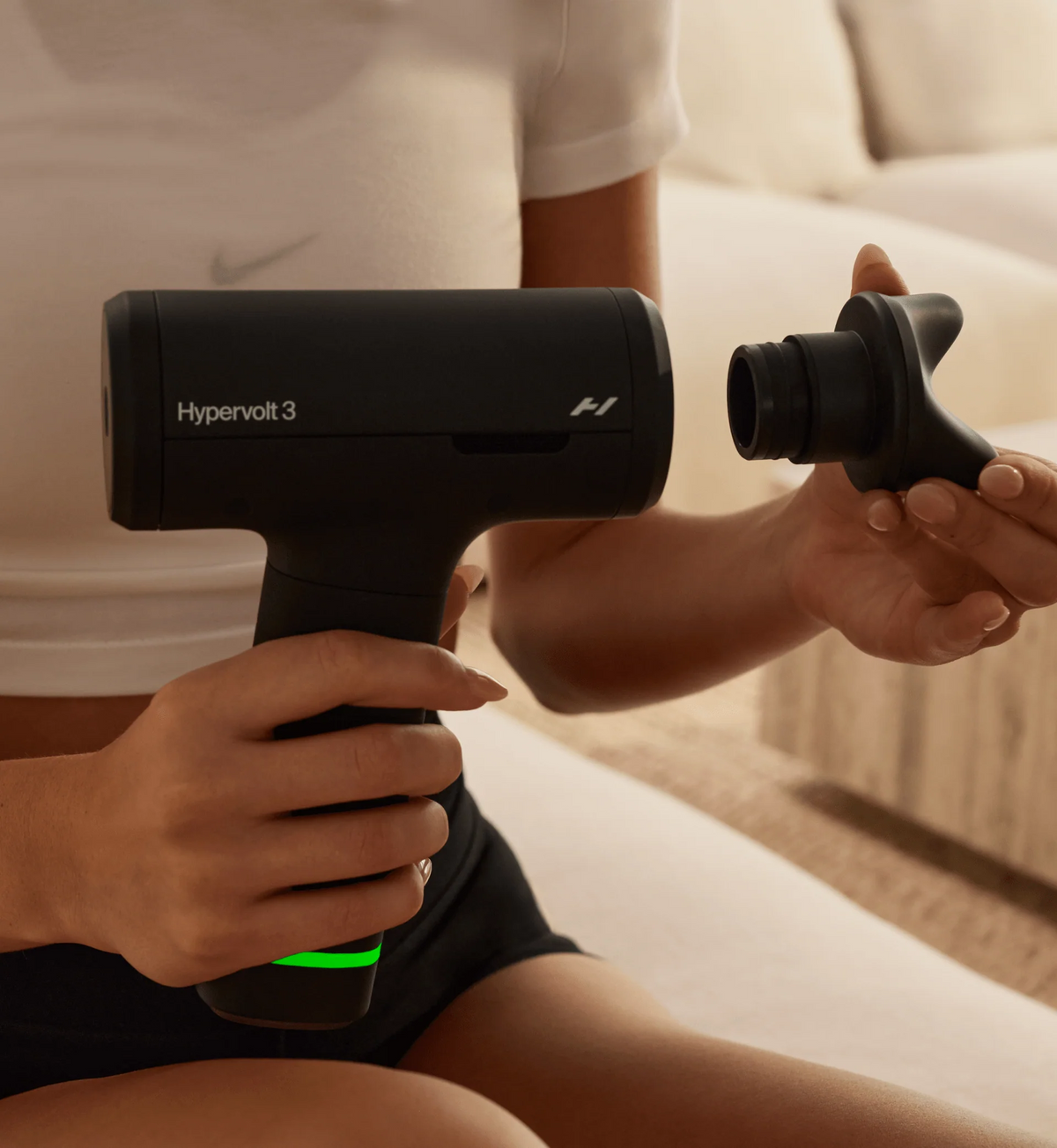 Person holding a Hypervolt 3 device on a couch