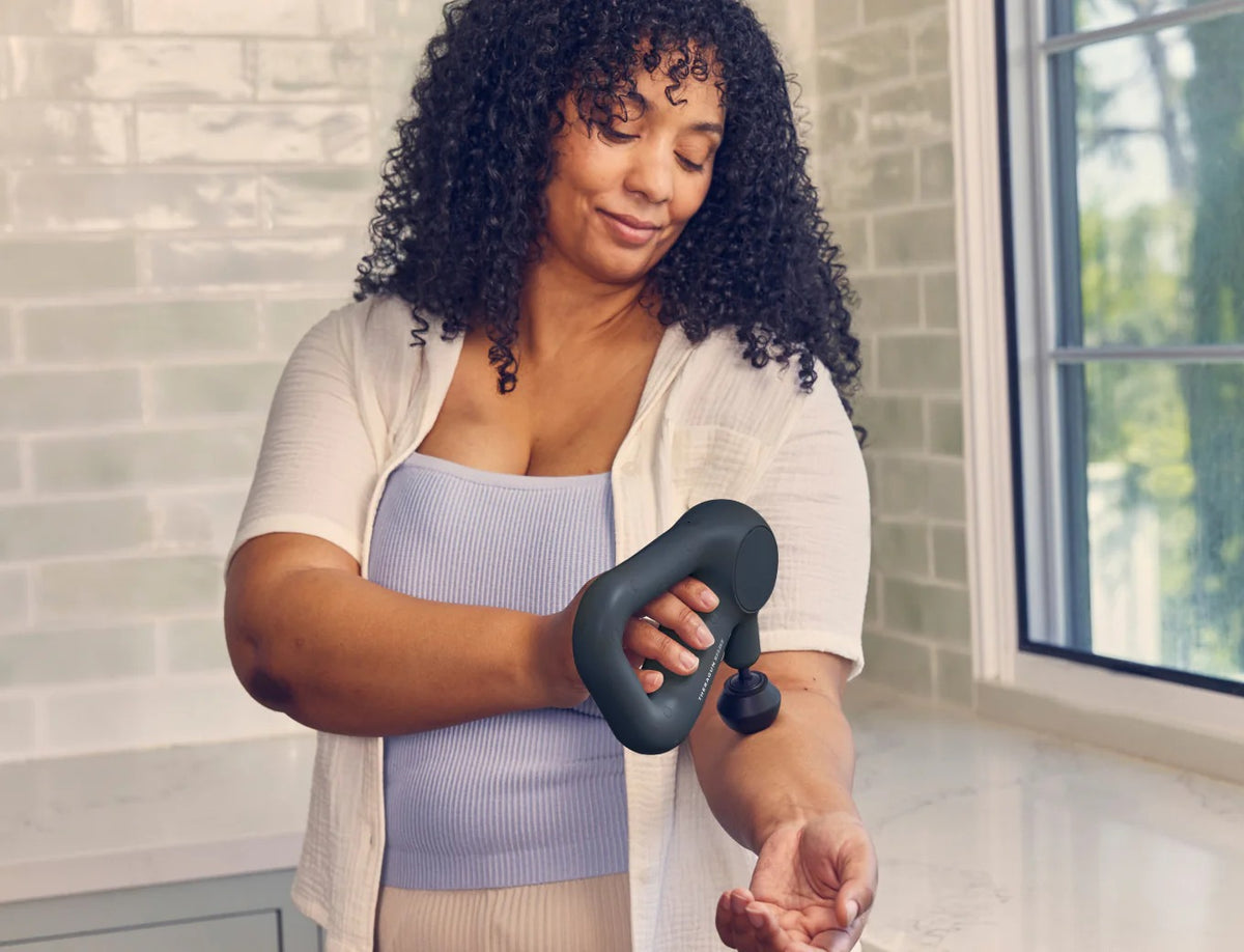 Person using Therabody Theragun Relief on shoulder muscles at home