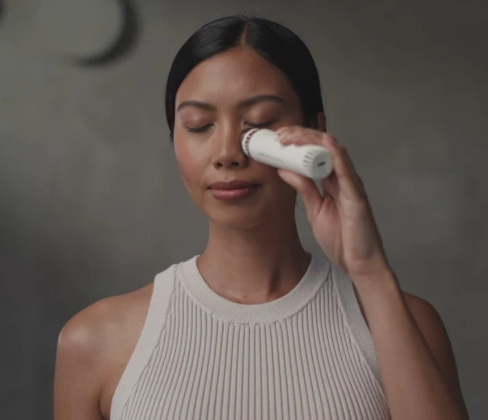 Woman using TheraFace Depuff device for under-eye cooling treatment and facial rejuvenation