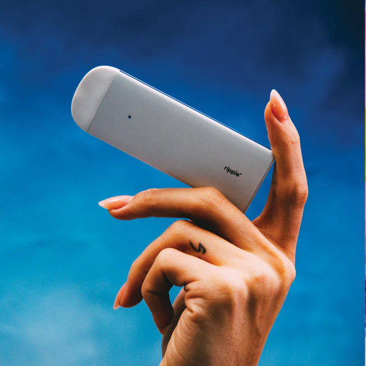 person holding Ripple vape device in hand sky background